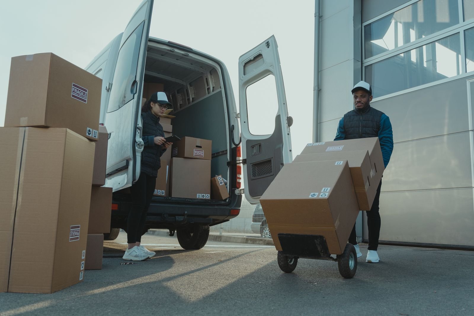 Manutentionnaire déchargeant des boîtes avec un diable devant un camion